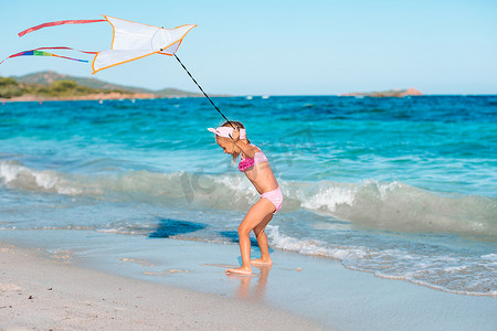 在热带海滩上放风筝的小奔跑女孩。