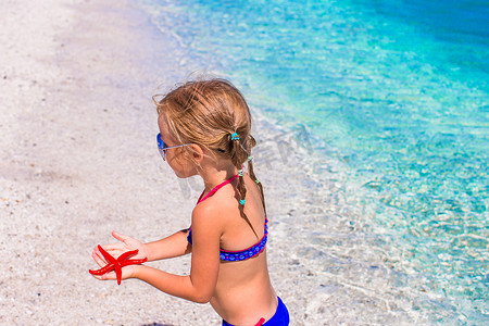 暑假期间在海滩上带海星的可爱小女孩