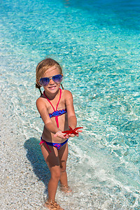 海星可爱摄影照片_热带海滩上有海星的可爱小女孩