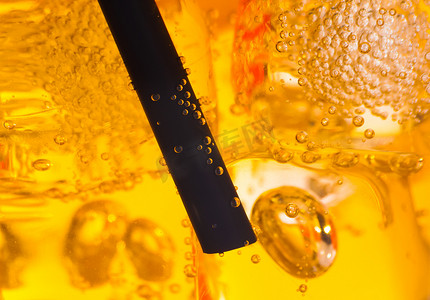 黄色鸡尾酒中稻草的特写，背景是冰块