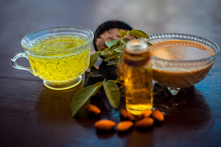 在玻璃碗中将恶魔粪粉或兴粉与绿茶和必需杏仁油充分混合的木质表面自制护发素以及表面的全部原料。