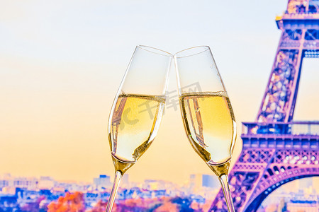 模糊的埃菲尔铁塔背景上一对带有金色气泡的香槟长笛