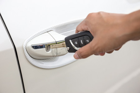 一个女人的手将钥匙插入一辆白色汽车的门锁的特写。（聚焦钥匙孔）