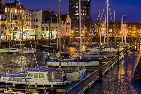 晚上的弗利辛根港有许多停靠的船只，装饰有灯光的船只，有水的灯火通明的城市建筑，荷兰泽兰的热门城市