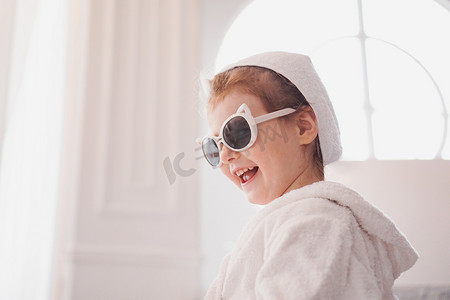 穿着浴袍和毛巾、太阳镜的小女孩。