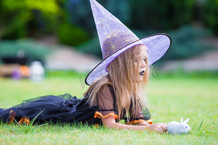 可爱的小女孩在万圣节的女巫服装在秋天的一天。