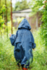 雨中儿童摄影照片_有趣的小男孩穿着带兜帽的雨衣在雨中行走，bl
