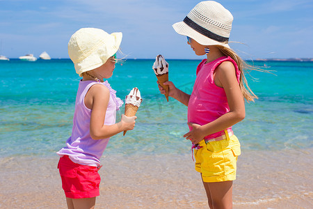 可爱冰淇淋摄影照片_在热带海滩上吃冰淇淋的小可爱女孩