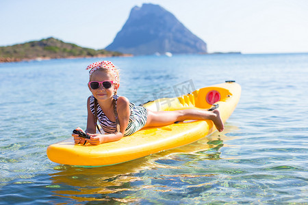 暑假期间在蓝色大海中划皮划艇的可爱小女孩