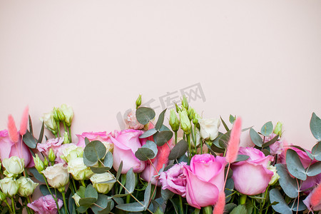 粉色花朵装饰摄影照片_浅粉色背景上有一束精致动人的白色和粉色花朵。
