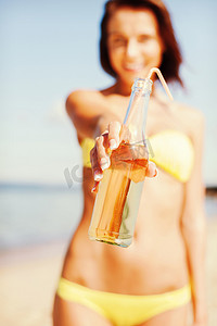 海滩上拿着一瓶饮料的女孩