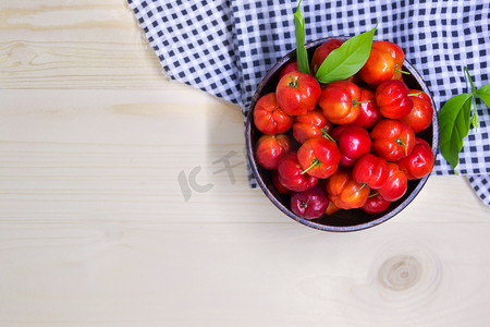 红色复古背景摄影照片_木碗中的甜樱桃浆果，桌上有格子呢面料，红色成熟多汁的甜樱桃位于复古木质背景、平躺、顶视图和文本复制空间、健康水果食品上。