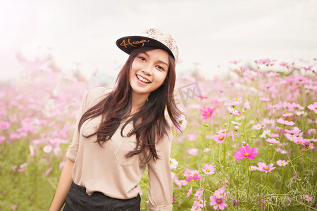 美丽的亚洲女性在粉红色的宇宙花田中微笑