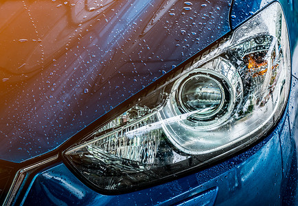 汽车广告设计摄影照片_具有运动和现代设计的蓝色紧凑型 SUV 汽车正在用水清洗。