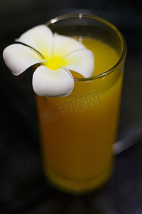 鲜榨鲜橙汁，特写是深色背景中玻璃上的玉兰花