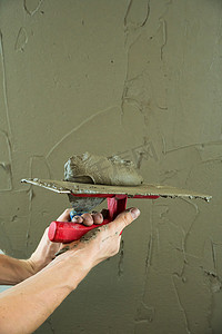 抹墙施工摄影照片_一名工人用抹刀抹墙，并涂上水泥 m