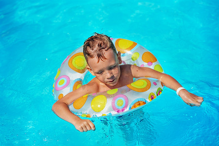 快乐的孩子在游泳池蓝色的水中玩耍。
