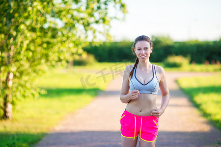 美丽的年轻运动女孩在户外跑步。
