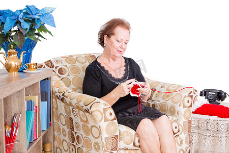 扶老人摄影照片_祖母坐在家里做她的编织