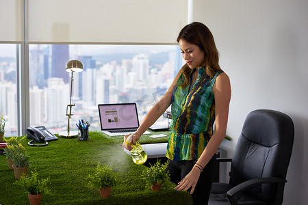 生态学家女商人在公司办公室给植物浇水