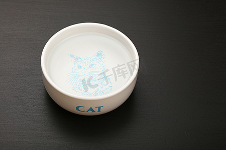 猫地板摄影照片_黑地板陶瓷碗里的猫水