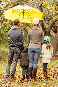 伞下年轻家庭的背面图