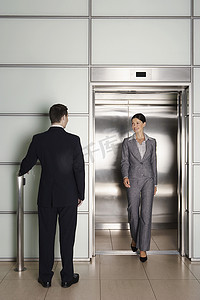 商人在办公室看着女同事离开电梯的后视图