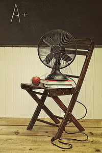 夏天扇子摄影照片_椅子上放着苹果和书的老扇子