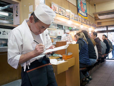 手绘寿司店摄影照片_筑地鱼市附近寿司店的服务员