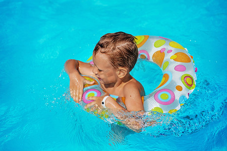快乐的孩子在游泳池蓝色的水中玩耍。