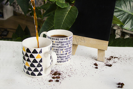 白色背景和植物背景上的热咖啡、咖啡豆和空黑板，工作室拍摄。