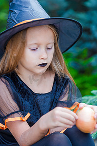 万圣节穿着带扫帚的女巫服装的可爱小女孩