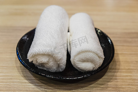 湿热摄影照片_黑色盘子上卷起的热湿毛巾 (oshibori)