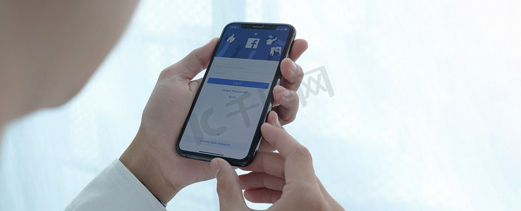 注册登录页面摄影照片_泰国清迈，2020 年 7 月 27 日：Facebook 社交媒体应用程序徽标登录、iPhone 智能设备移动应用程序屏幕上的注册页面在商务人员手中工作