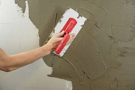 一名工人用抹刀抹墙，并涂上水泥 m