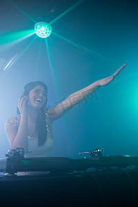 dj酒吧摄影照片_漂亮的女 DJ 在播放音乐时挥舞着她的手