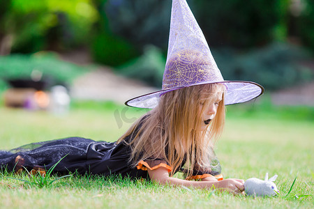 可爱的小女孩在秋天的万圣节穿着女巫服装。