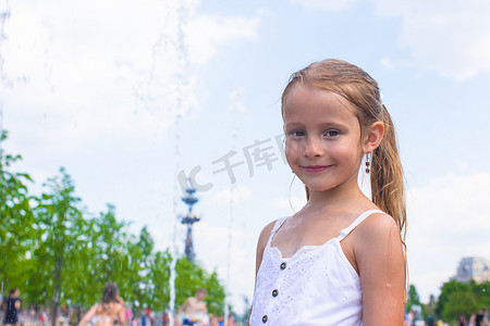 清爽一夏天摄影照片_小女孩在炎热的天气里在户外喷泉里玩得开心
