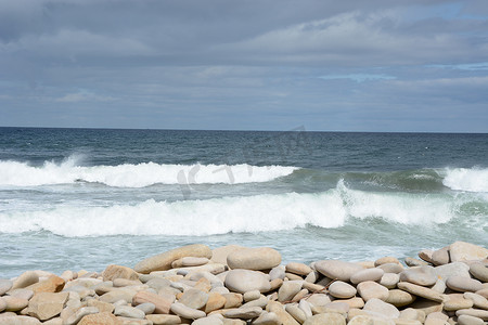 海浪汹涌摄影照片_平坦的海面磨损的鹅卵石和汹涌的海浪