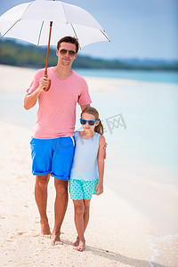 父亲和孩子在海滩上用遮阳伞遮阳