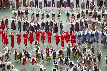 儿童表演摄影照片_身着传统服饰的舞者在道加瓦体育场举行的拉脱维亚青年歌舞节盛大民间舞蹈音乐会上表演。