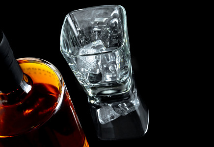 黑色背景中靠近瓶子的空威士忌玻璃杯的顶部视图