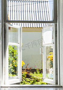 从阳光明媚的夏日庭院的古老乡村窗户望去