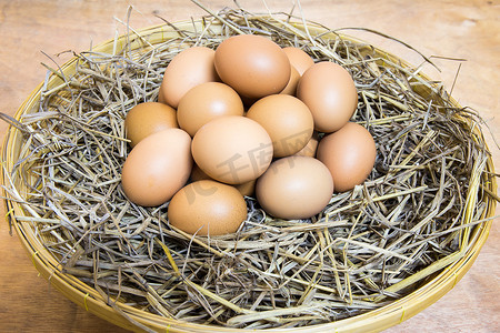 在养鸡场的木桌上的篮子里的干草窝里的棕色鸡蛋