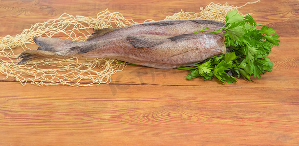 松鼠鱼菜摄影照片_木质表面上未煮熟的无须鳕尸体