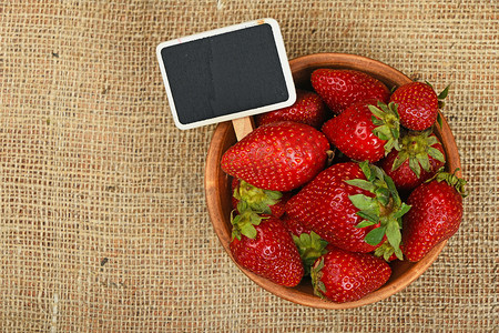 白盘子摄影照片_碗里的草莓和画布上的价格标志