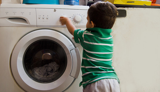 洗衣服男孩摄影照片_一岁半男婴把衣服放进洗衣机