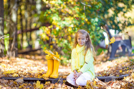 可爱黄人摄影照片_美丽的秋日，带黄枫叶的可爱小女孩在户外