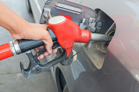红色燃料喷嘴在加油站将燃料释放到汽车中并继续