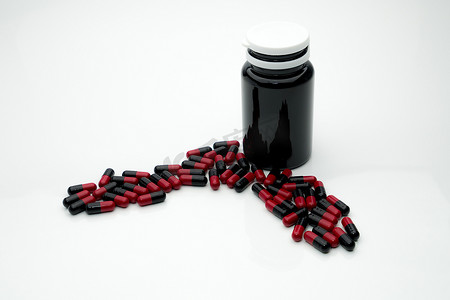 红色、黑色抗生素胶囊丸和棕色塑料瓶隔离在白色背景上，具有复制空间、耐药性概念
